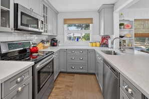 A modern kitchen with grey cabinets, stainless steel appliances, and a window with a view. - Downtown Rehoboth Beach House Quick Walk to Beach Pets Permitted (Rehoboth Beach)