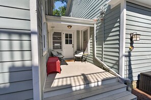 A covered porch with a door, a small seating area with a chair and table, and a wall-mounted light fixture. - Downtown Rehoboth Beach House Quick Walk to Beach Pets Permitted (Rehoboth Beach)