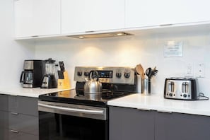 A modern kitchen with a stainless steel stove, a coffee maker, a toaster, and a kettle. - Private Pool | No Carpet | Walk to Walmart | Spotless (Kissimmee)