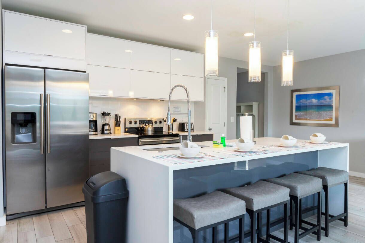 A modern kitchen with a central island, stainless steel appliances, and pendant lighting.