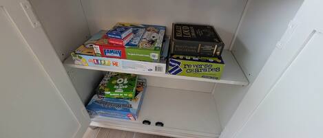 A shelf with various board games, including 'Family Challenge' and 'Guess in 10'.