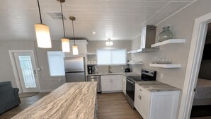 Une cuisine moderne avec des meubles blancs, un plan de travail en marbre et des luminaires suspendus.