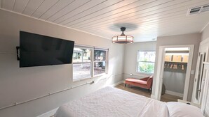 Une chambre à coucher avec un lit, un téléviseur fixé au mur et une fenêtre.