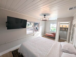 Ein Schlafzimmer mit einem Bett, einem an der Wand montierten Fernseher und einem Fenster.