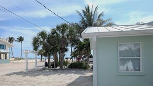 Une propriété située en bord de mer, comprenant un petit bâtiment, des palmiers et une promenade pavée.