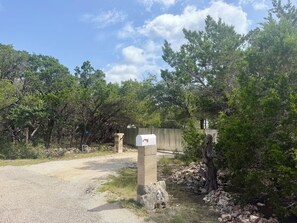 A gravel path leading to a gated area with a mailbox and a stone pillar marked with the number 700.