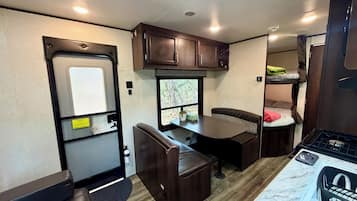 An RV interior with a kitchen area, seating, and a window.