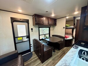 An RV interior with a kitchen area, seating, and a window.