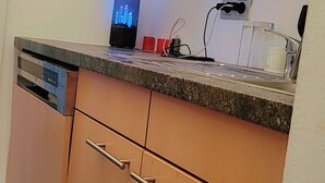 A kitchen with wooden cabinets, a dishwasher, a countertop with a coffee maker, and a power outlet. - Ein Zimmer in 2 Wohnung Zimmer (Vienna)