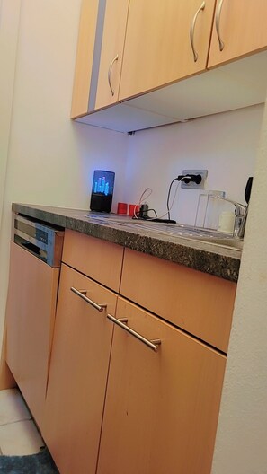 A kitchen with wooden cabinets, a dishwasher, a countertop with a coffee maker, and a power outlet. - Ein Zimmer in 2 Wohnung Zimmer (Vienna)