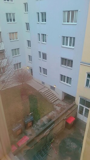 A multi-story building with a flat facade, multiple windows, and a small courtyard with steps leading to the entrance. - Ein Zimmer in 2 Wohnung Zimmer (Vienna)