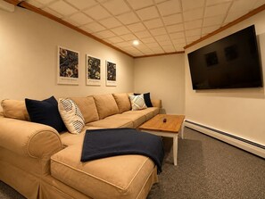 Ein Wohnzimmer mit einem beigefarbenen Sofa, einem Couchtisch und einem flachbildfernseher an der Wand.