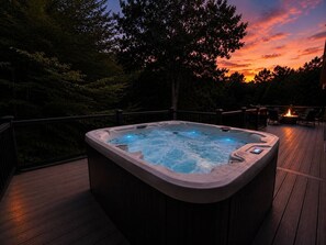 Un bain à remous sur une terrasse en bois, avec un coucher de soleil en arrière-plan.