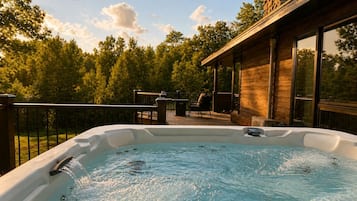 A hot tub on a deck with a wooden house in the background.