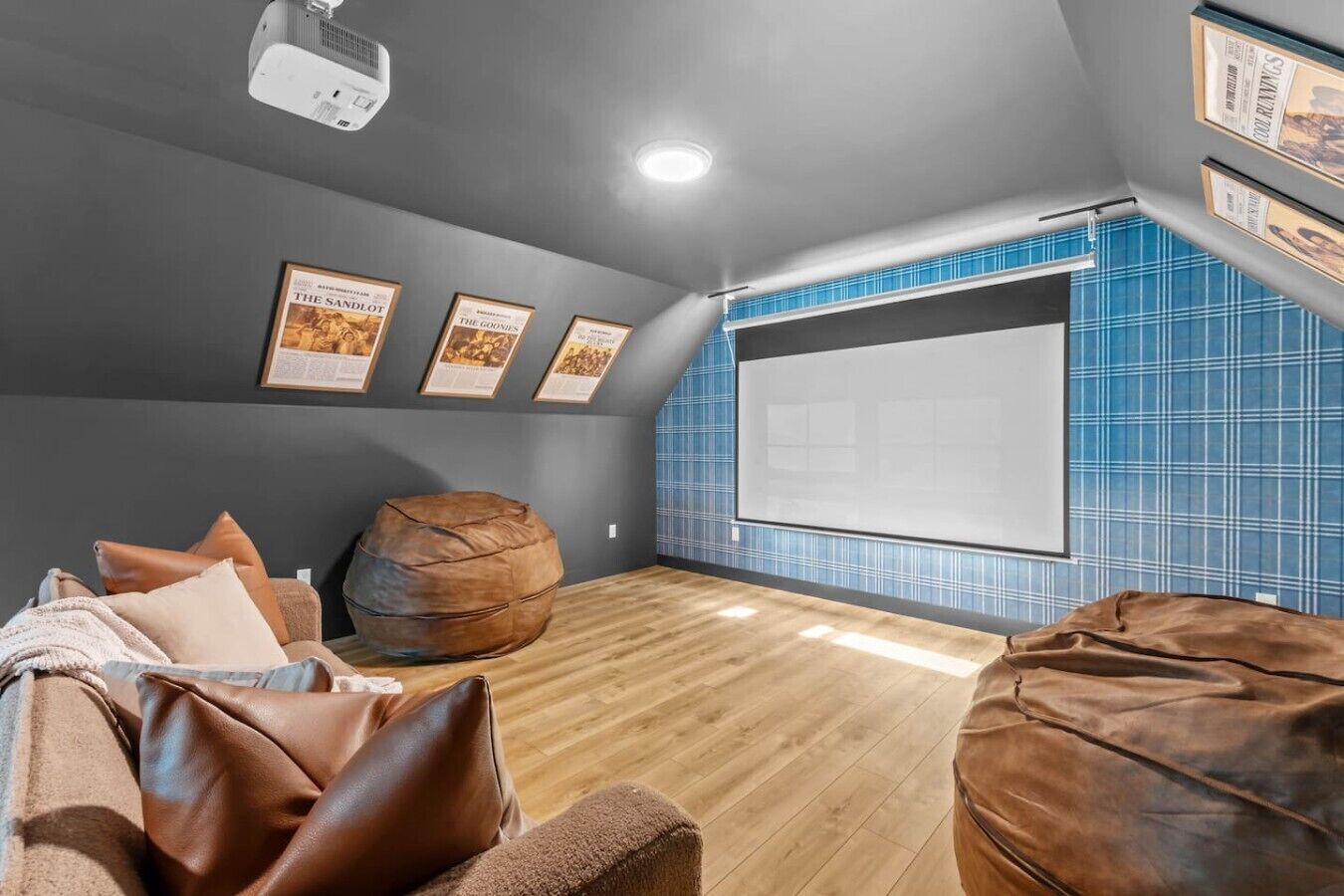 A home theater room with a large screen, bean bag chairs, and framed movie posters on the wall.