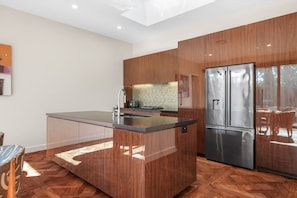 A modern kitchen with a central island, stainless steel appliances, and wooden cabinetry. - Peaceful Coastal Escape near Beach (Cowes)