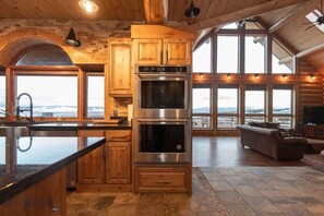 A spacious kitchen with a large island, built-in oven, and wooden cabinetry.