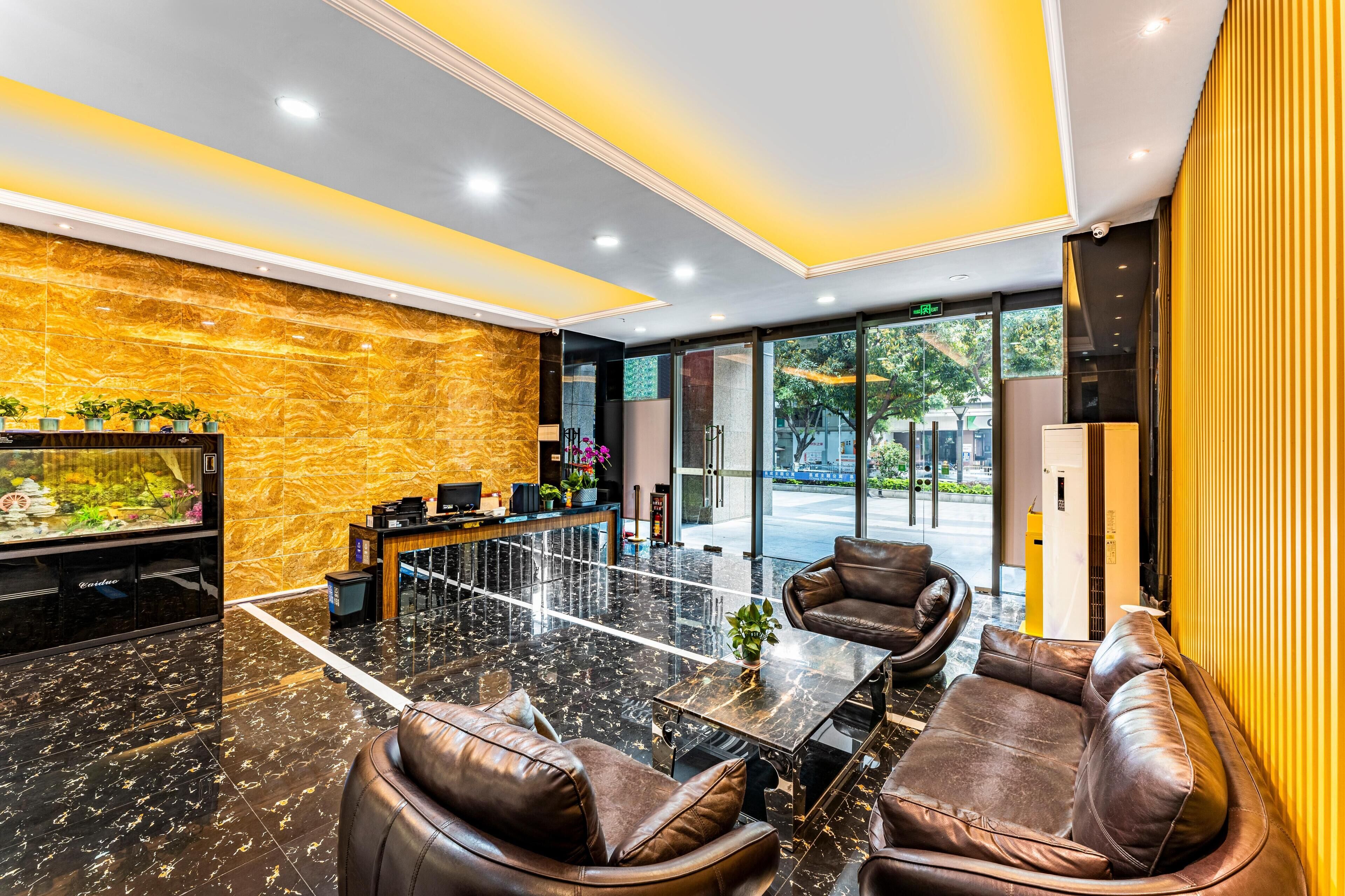 A modern lobby with a reception desk, leather seating, a fish tank, and a view of the outdoors.