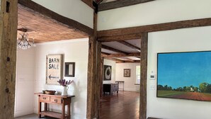 A rustic interior with exposed wooden beams, a 'Barn Sale' sign, a painting, and a patterned rug. - Historic 1789 Luxury Farmhouse near Dartmouth College (Hartford)