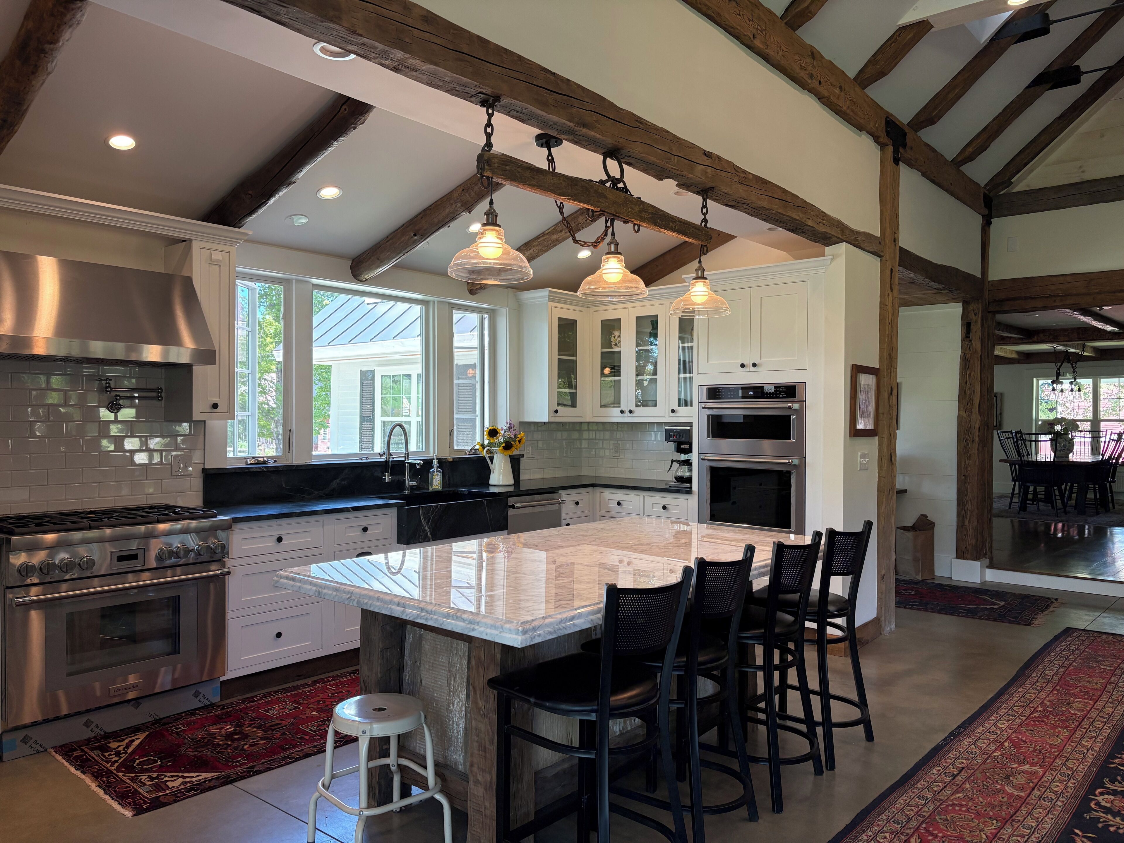 A modern kitchen with a large island, stainless steel appliances, and pendant lighting.