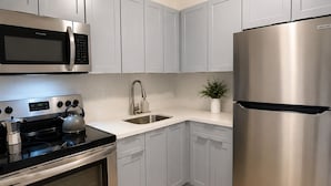 A modern kitchen with grey cabinets, stainless steel appliances, and a tiled floor. - Beautiful & Central Cozy Home (Miami)