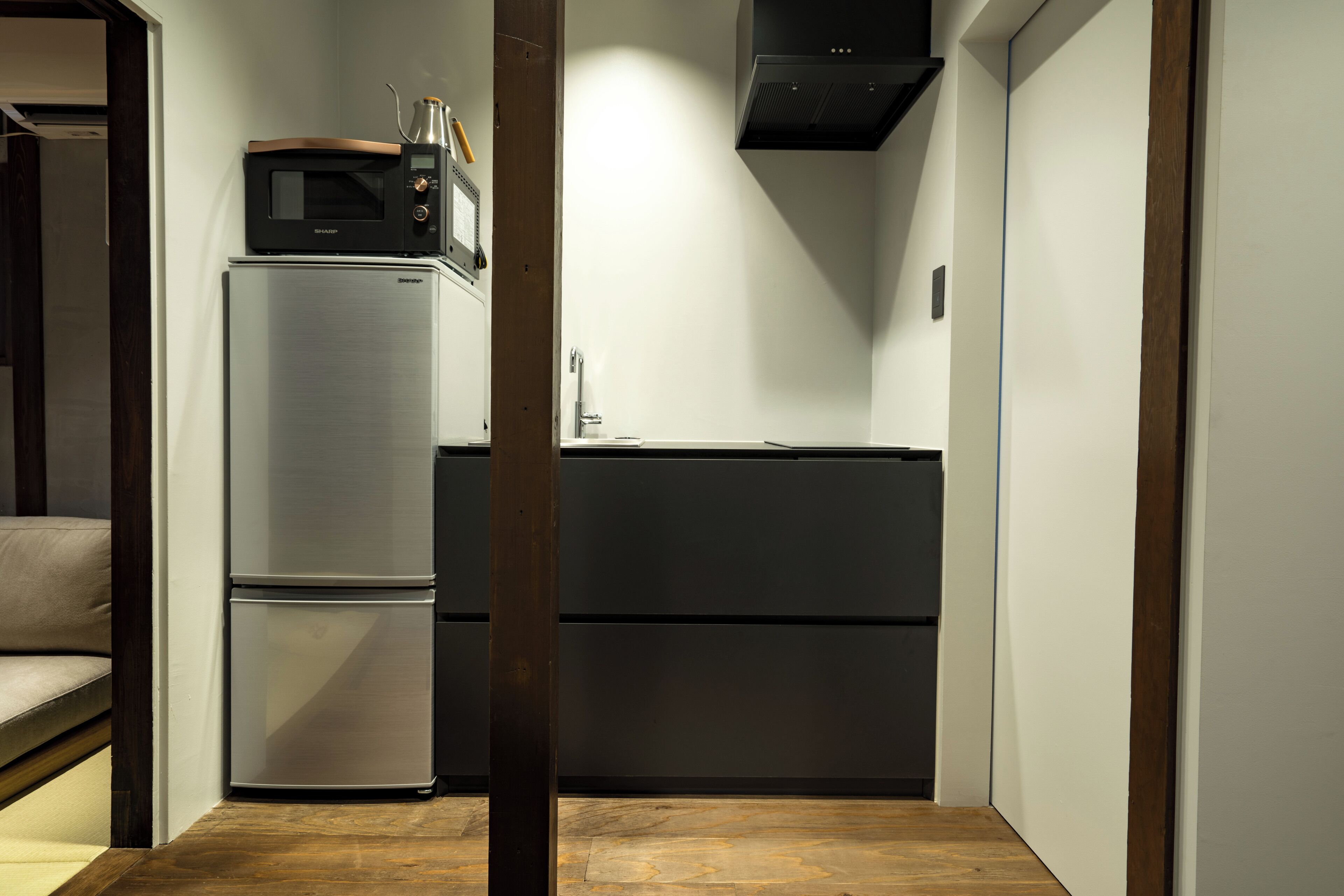A compact kitchen with a stainless steel refrigerator, a microwave, and a built-in oven.