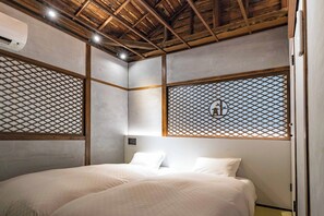 Une pièce avec un lit, des poutres en bois au plafond et un mur orné d’un motif géométrique.