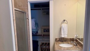 Un bagno con doccia, lavandino con piano in marmo, porta asciugamani e specchio.