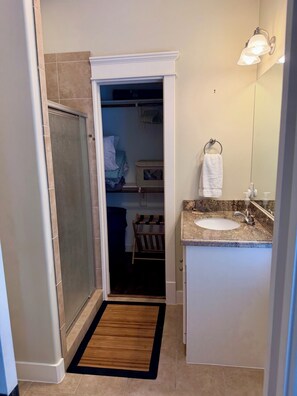 Ein Badezimmer mit Dusche, Waschbecken mit Marmorplatte, Handtuchhalter und Spiegel.