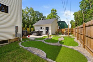 A backyard with a small shed, a grill, and a fenced play area. - Station580 | 8 min OSU | Hot Tub, Mini Golf, Games (Columbus)