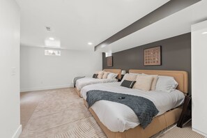 A modern bedroom with two beds, a patterned carpet, and artwork on the walls. - Station580 | 8 min OSU | Hot Tub, Mini Golf, Games (Columbus)