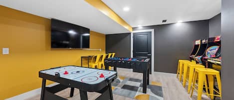 Une pièce équipée d’un baby-foot, d’une table de ping-pong et d’un téléviseur fixé au mur.