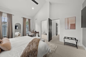 A modern hotel bedroom with a large bed, a desk, and a bathroom visible through an open door. - Station580 | 8 min OSU | Hot Tub, Mini Golf, Games (Columbus)