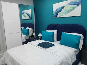 A bedroom with a bed, a nightstand, a mirror, and artwork on the wall. - 2-bedroom Residences meublees in soothing Bouake with AC comfort (Bouake)