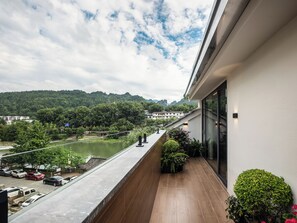 A balcony with a view of a river, trees, and a hilly landscape. - Zhangjiajie Ruyuan Hotel  (Zhangjiajie)