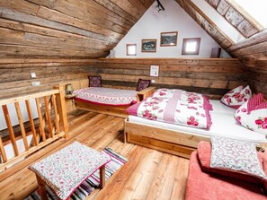A cozy attic bedroom with wooden walls, a loft bed, a small table, and a bench. - Franzosenstüberl - Uriger Troadkasten by Interhome (Rennweg am Katschberg)