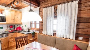 A cozy kitchen with wooden cabinets, a dining table with a placemat, and a window with curtains. - Franzosenstüberl - Uriger Troadkasten by Interhome (Rennweg am Katschberg)