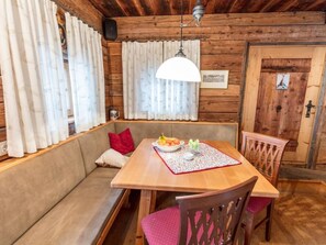A wooden cabin interior with a wooden dining table, bench seating, and a hanging light fixture. - Franzosenstüberl - Uriger Troadkasten by Interhome (Rennweg am Katschberg)