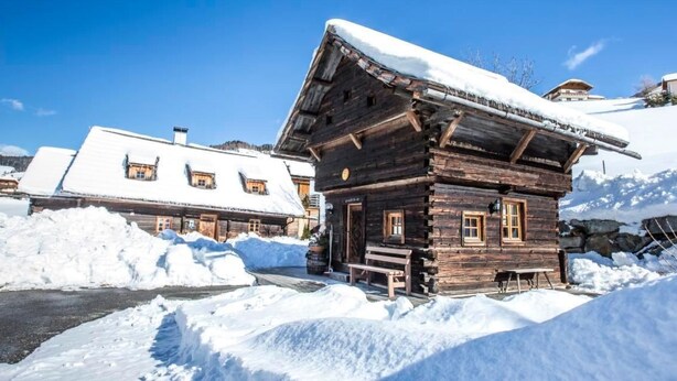 A wooden cabin with a snow-covered roof, surrounded by snow, and a clear blue sky. - Franzosenstüberl - Uriger Troadkasten by Interhome (Rennweg am Katschberg)
