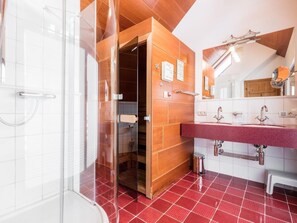 Een moderne badkamer met een douchecabine van glas, een houten wastafelmeubel en een vloer van rode tegels.