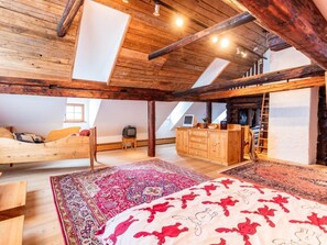 A spacious attic bedroom with a large bed, a wooden wardrobe, and a desk.