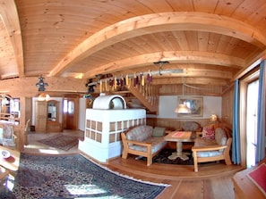 Ein Holzinnenraum mit einer Couch, Sesseln, einem Tisch und einem Kamin.