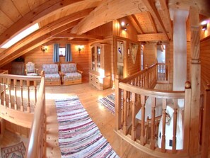 Un intérieur en bois avec un escalier, un ensemble de canapés et un tapis à motifs.