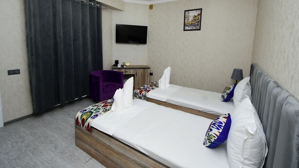 A hotel room with two beds, a desk, a chair, a television, and a picture on the wall. - Samarqand Darvoza (Bukhara)