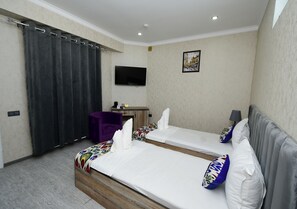 Une chambre d’hôtel avec deux lits, un bureau, une chaise, une télévision et un tableau au mur.