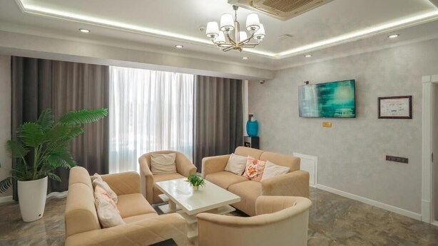 Una sala de estar moderna con sofás color beige, una mesa de centro blanca y un ventanal con cortinas.