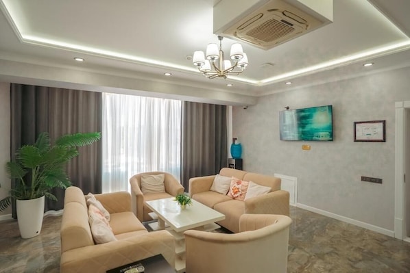 A modern living room with beige sofas, a white coffee table, and a large window with curtains. - Samarqand Darvoza (Bukhara)