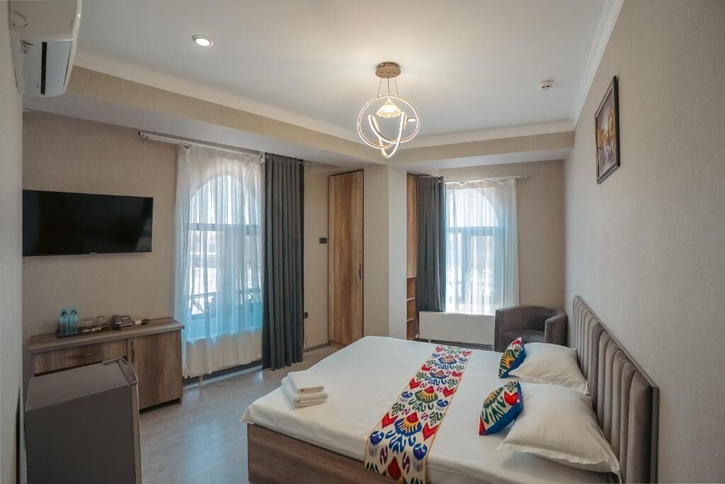 A hotel room with a bed, a desk, a chair, a television, and a ceiling light fixture.