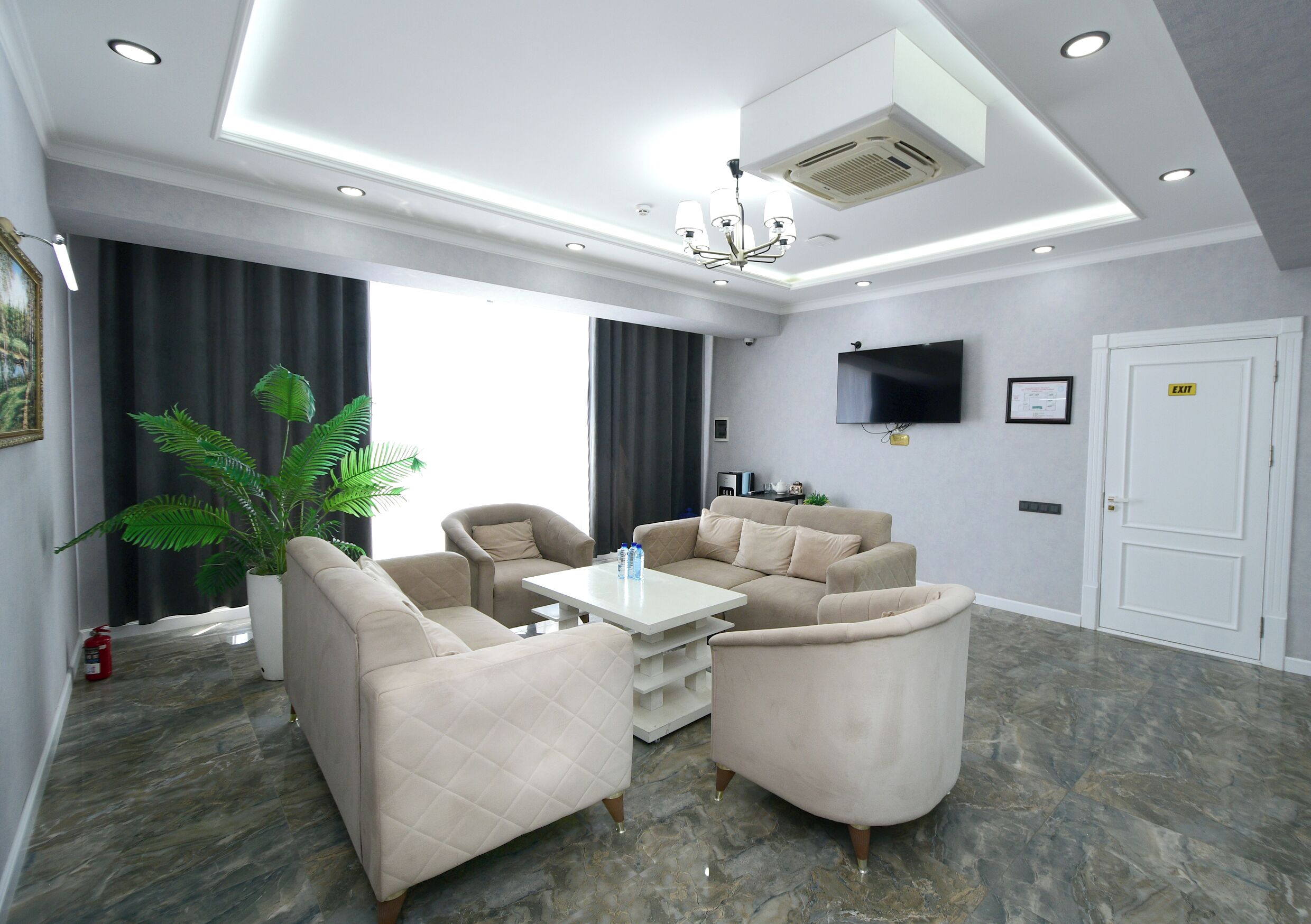A modern living room with a sectional sofa, a coffee table, and a flat-screen TV mounted on the wall.