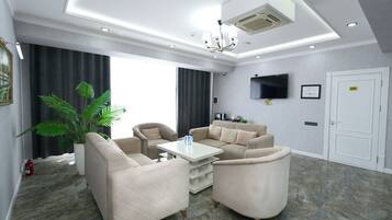 A modern living room with a sectional sofa, a coffee table, and a flat-screen TV mounted on the wall.